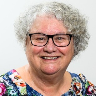 Portrait of Dr Candy Cookson‑Cox (Te Arawa, Kāi Tahu, Kahungunu) wearing a patterned top, photographed against a plain background.